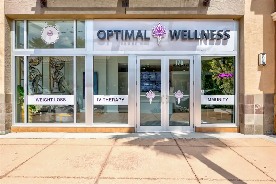 Glass entrance doors lettered OPTIMAL WELLNESS with WEIGHT LOSS, IV THERAPY and IMMUNITY decals across the lower panels